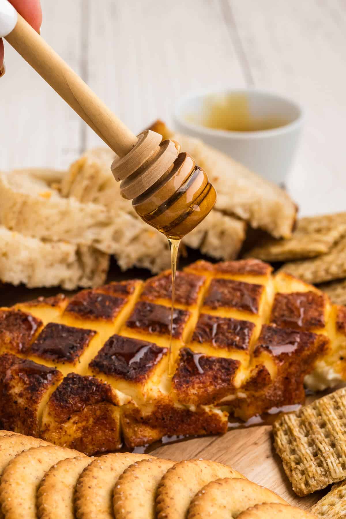 A honey dipper drizzling honey on top of freshly smoked cream cheese.