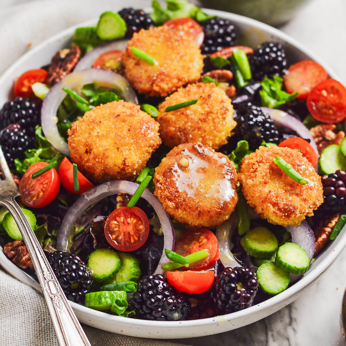 Crispy goat cheese topped on a bed of mixed greens, onions, sliced cucumbers, blackberries and cherry tomatoes. It's drizzled with Dijon Vinaigrette.