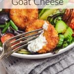 A fork cutting into a piece of fried goat cheese on a salad. Text overlay reads: Fried Goat Cheese.