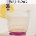 A glass of lavender lemonade before it's stirred so it has a layered appearance. There is a layer of purple on the very bottom of the glass, then the layer of lemonade which is light yellow. It is garnished with a slice of lemon and a lavender sprig. Text overlay reads: lavender lemonade mocktail.