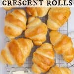 Homemade crescent rolls cooling on a wire rack, surrounded by a dish of butter and a small bowl of marmalade. Text overlay reads “Homemade Crescent Rolls.”