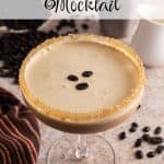 Espresso martini mocktail in a coupe glass with a sugared rim and frothy top, garnished with three coffee beans. A cocktail shaker, cream pitcher, and scattered coffee beans are in the background. Text overlay reads: Espresso Martini Mocktail