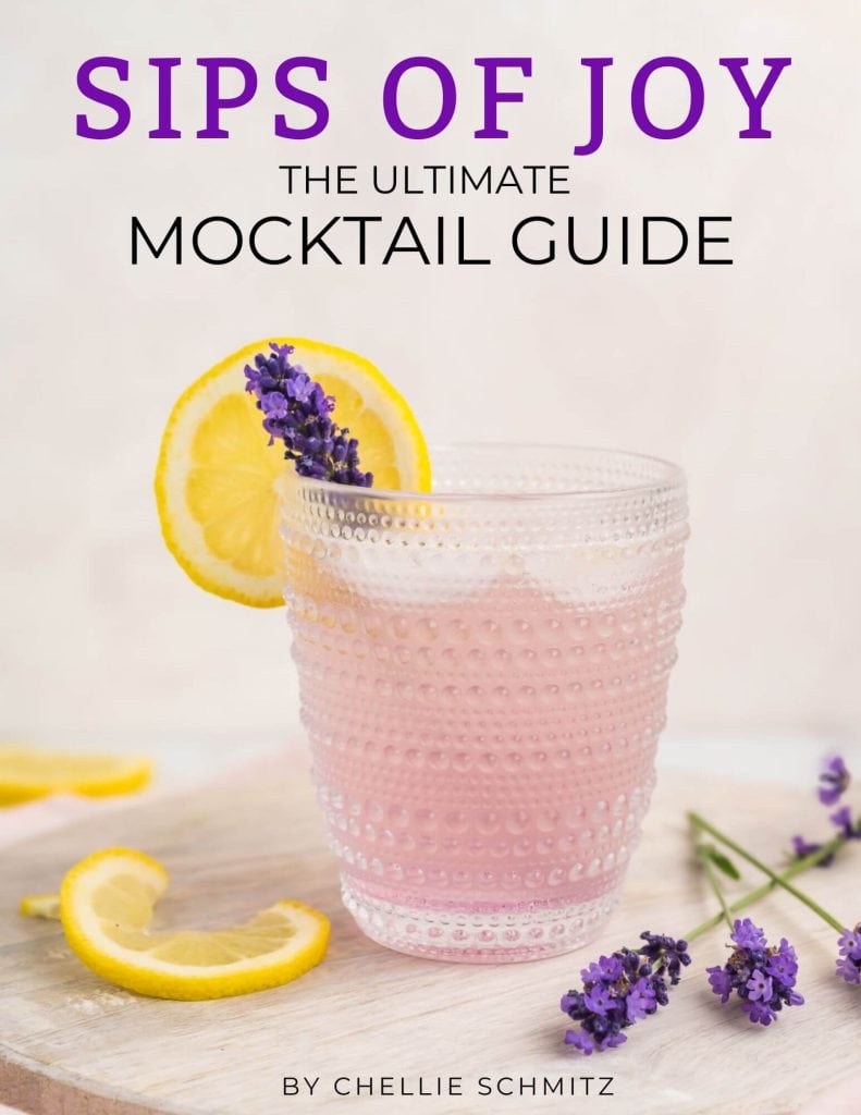 Lavender Lemonade Mocktail garnished with a lemon slice and fresh lavender. Text reads: Sips of Joy The Ultimate Mocktail Guide by Chellie Schmitz