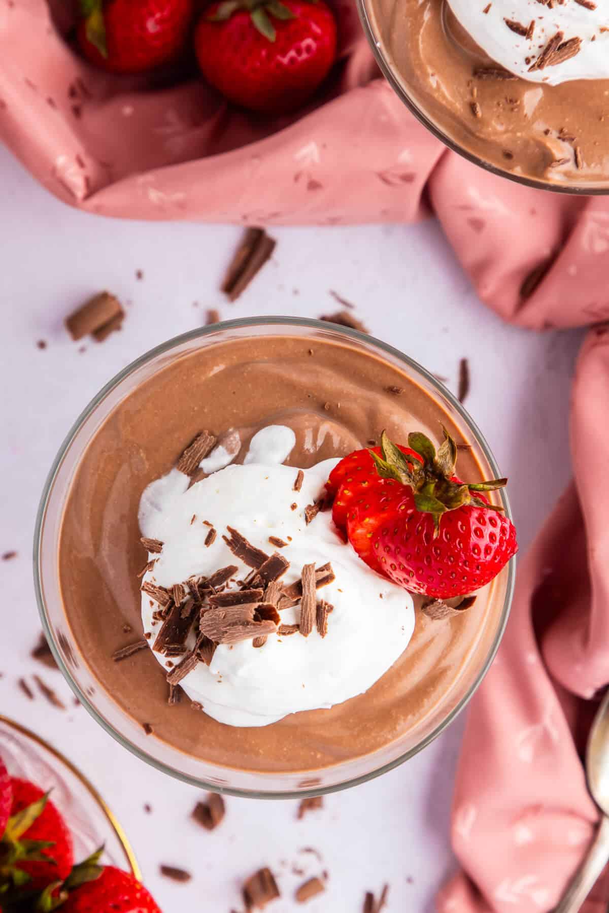 Top view of Cottage cheese chocolate mousse in a dessert glass topped with whipped cream, chocolate shavings, and garnished with a sliced strawberry.