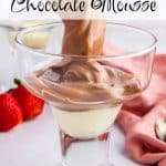 A spoon dropping a dollop of Cottage Cheese Chocolate Mousse into a dessert glass. Fresh strawberries in the back ground and a pink table linen. Text overlay reads: Cottage cheese Chocolate Mousse.